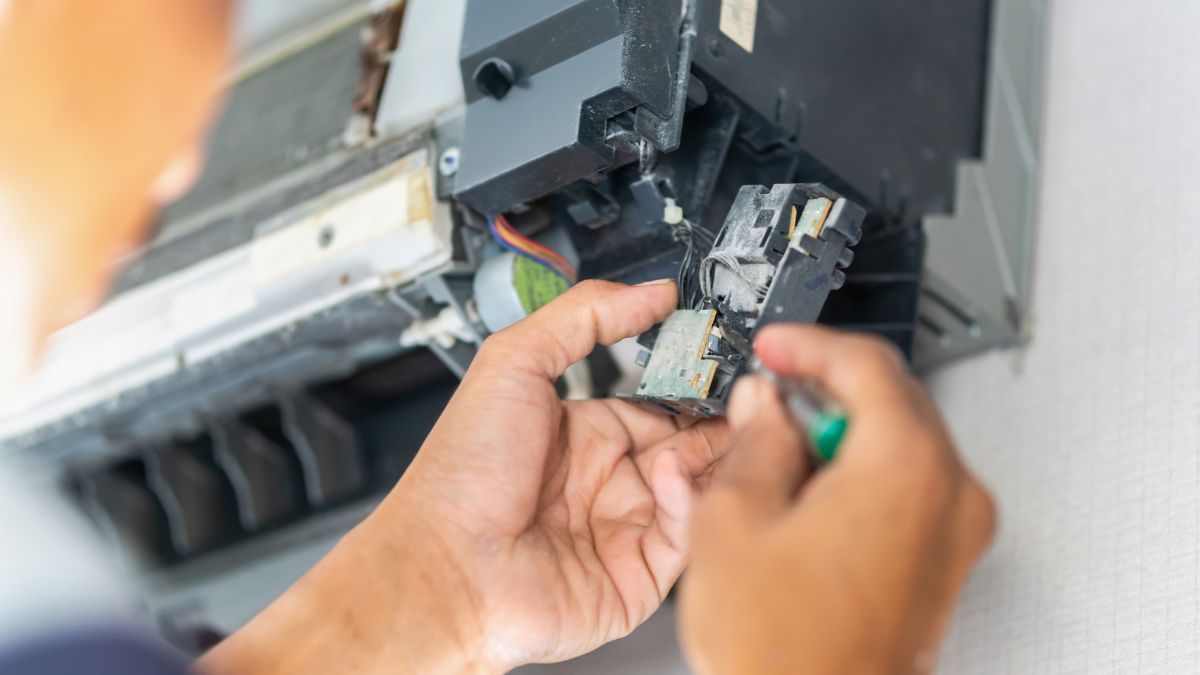 Un tehnician repară un termistor într-un aparat de aer condiționat.